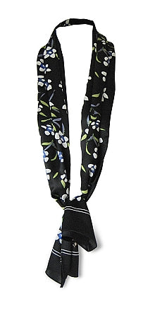 Silk scarf with white floral design on black background tied in classic neck style